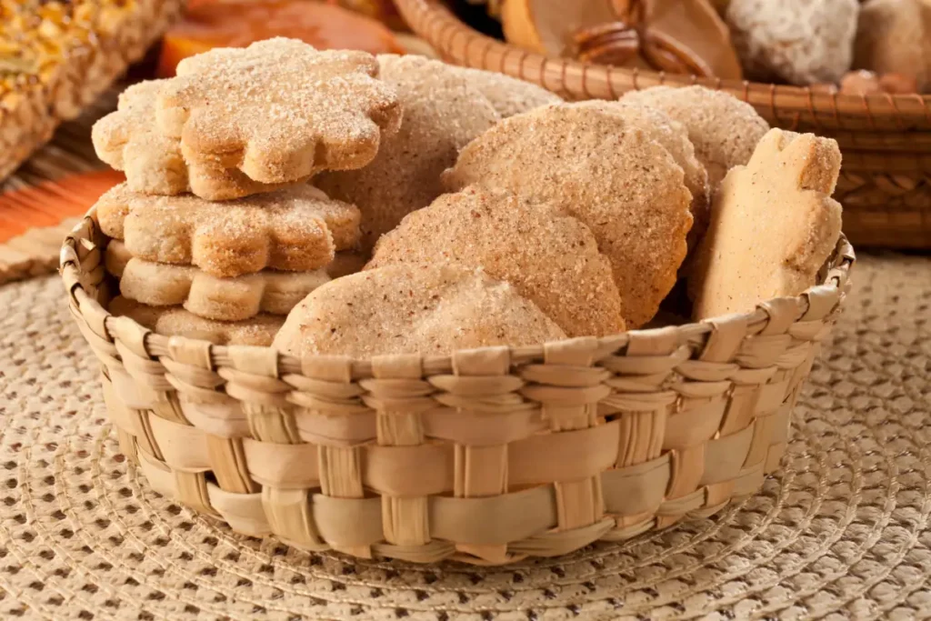 A woven basket containing various shapes of sugar-coated Mexican cinnamon cookies