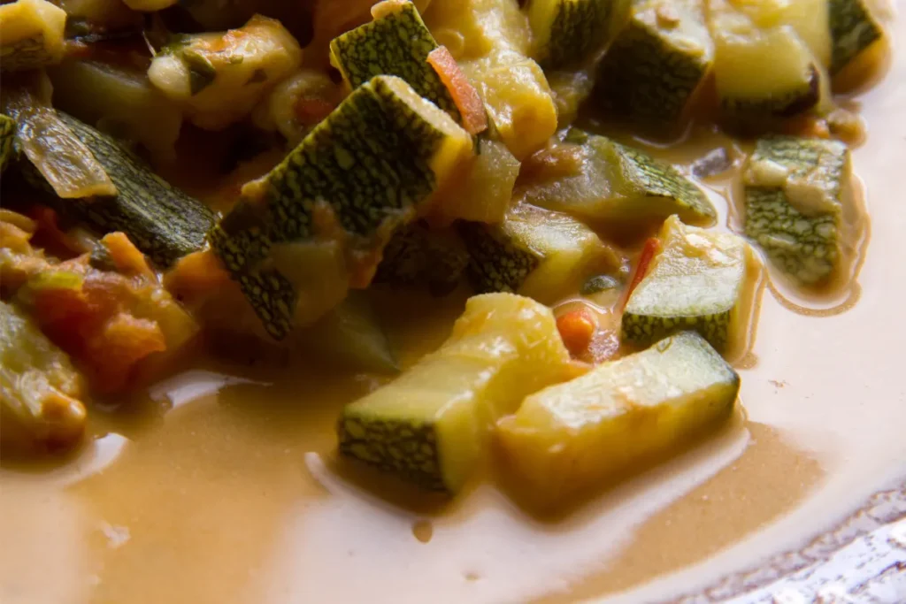 Macro shot of Calabacitas, showcasing the texture of the diced zucchini, melted cheese, and tomatoes, with a slight cheese pull visible.