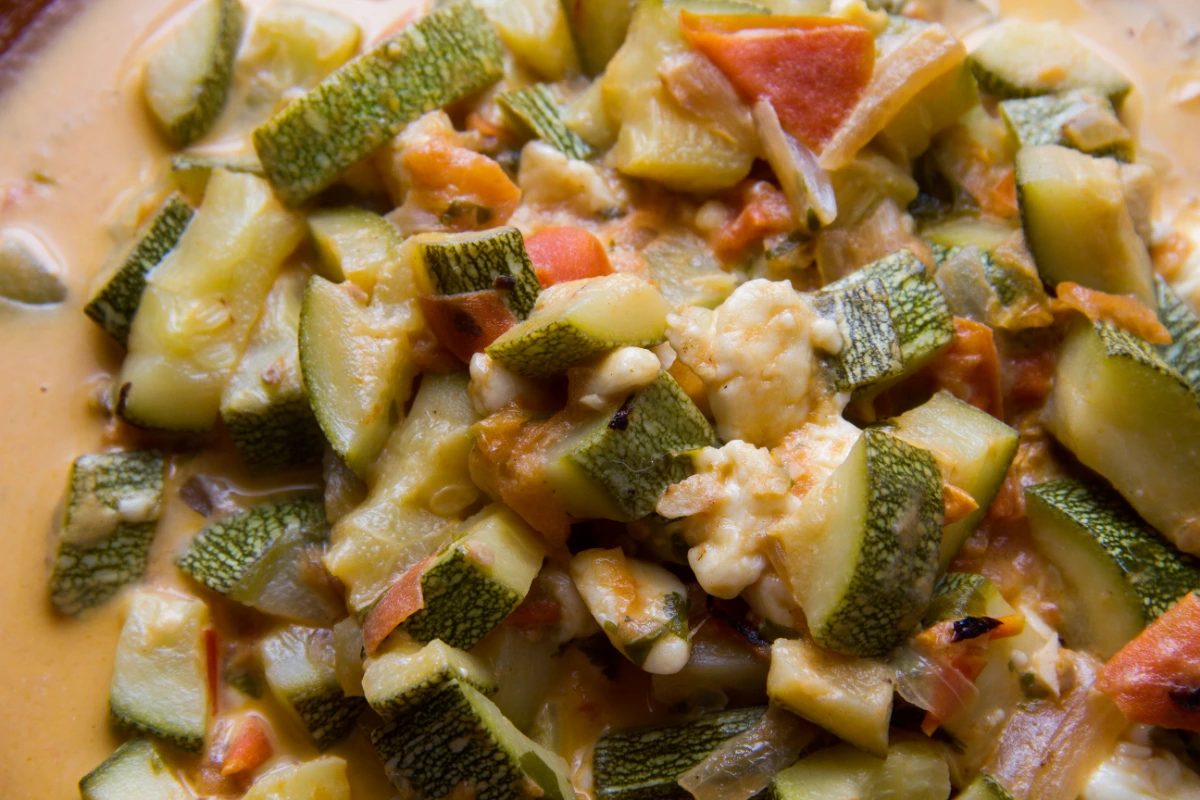 Close-up view of a dish called Calabacitas, consisting of diced zucchini, tomatoes, and melted cheese, indicative of a traditional Mexican side dish.