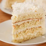 Slice of coconut cake on a white plate.