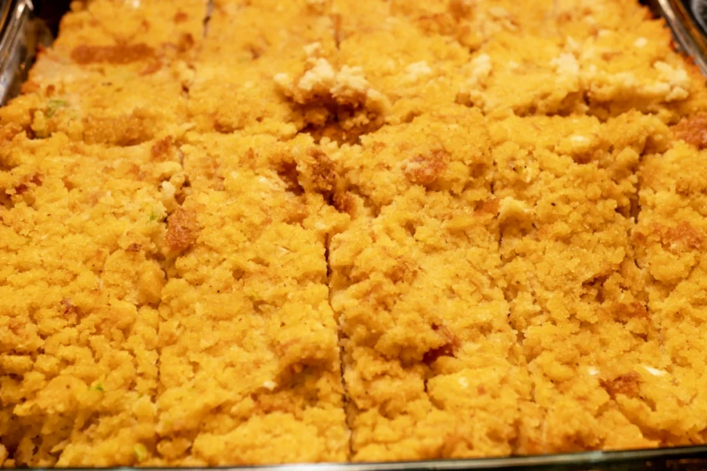 Close-up of a cornbread casserole with a golden-brown crust, freshly baked in a glass dish.