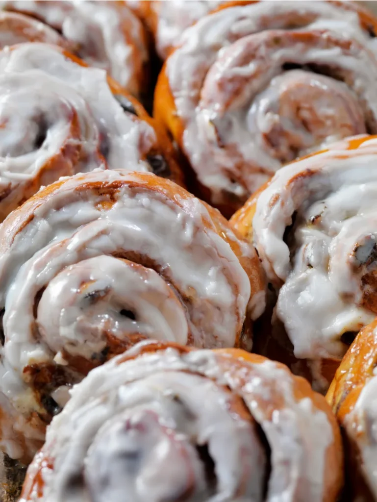 Close-up view of air fryer cinnamon rolls covered in creamy icing, highlighting the swirls and rich texture.