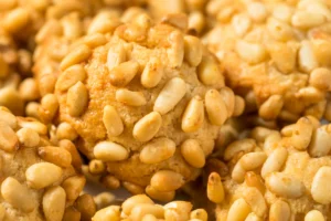 Close-up of pignoli cookies, showcasing their golden-brown surface and embedded pine nuts.