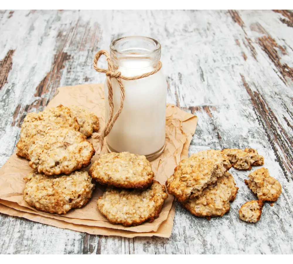 Rustic presentation of homemade cake mix cookies on parchment paper with a bottle of milk, on a distressed wooden surface.