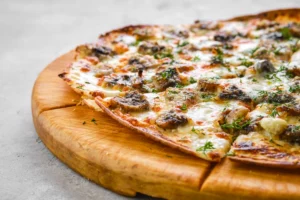 Close-up of a thin-crust pizza with melted cheese and sprinkled herbs on a wooden board, with a focus on the textured toppings and golden-browned crust.