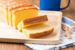 Sliced butter cake on a wooden cutting board, with two pieces placed in front and a blue mug in the background.