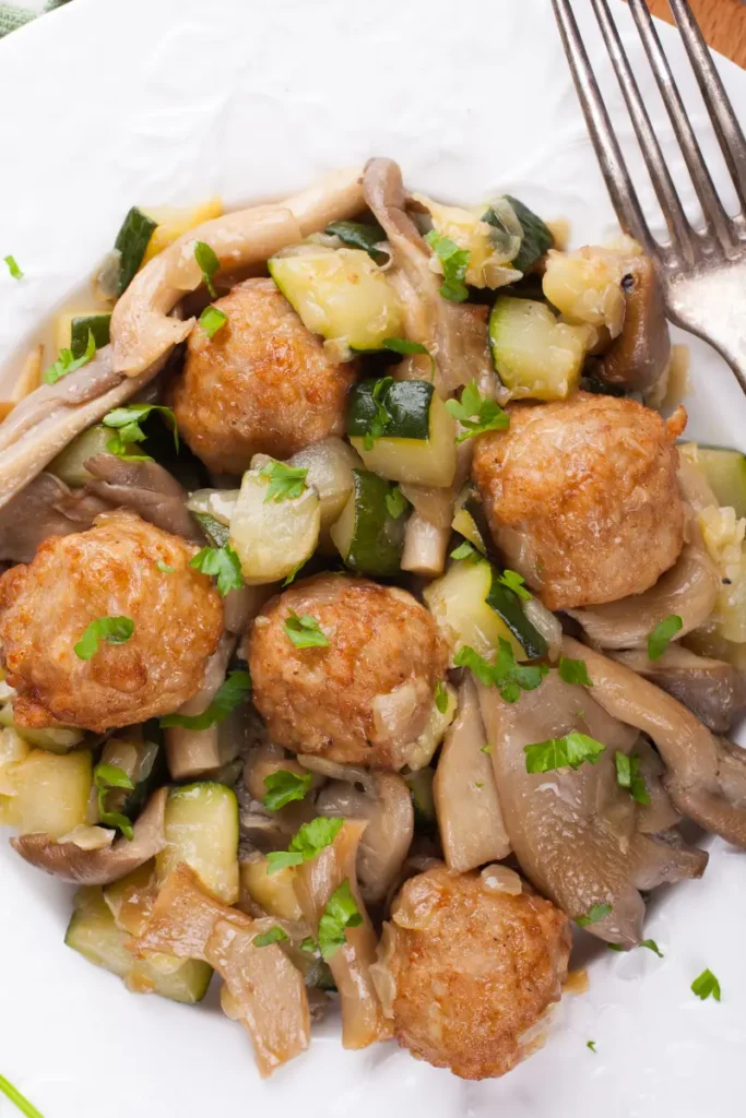 Plate of meatballs with oyster mushrooms and zucchini.