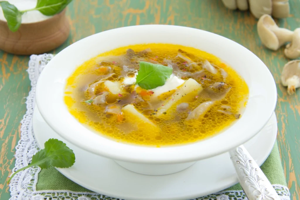 Bowl of oyster mushroom soup garnished with herbs.